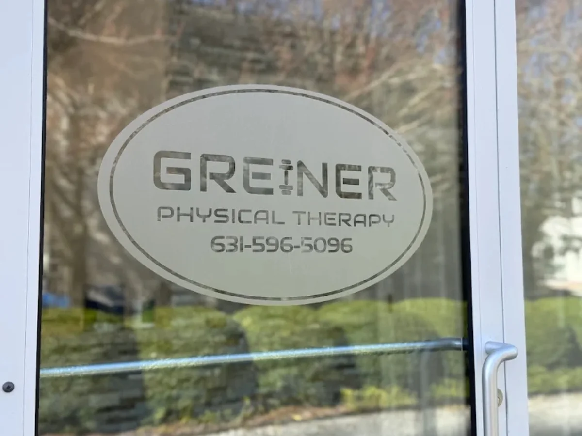 The Greiner Physical Therapy logo etched on the glass door of the Quogue office
