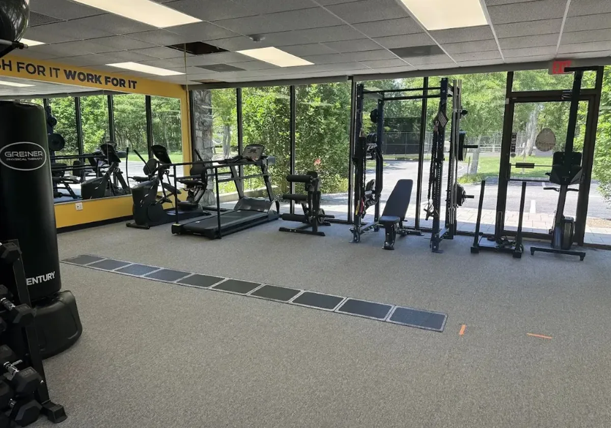 Treadmills lined up against tall sunlit windows