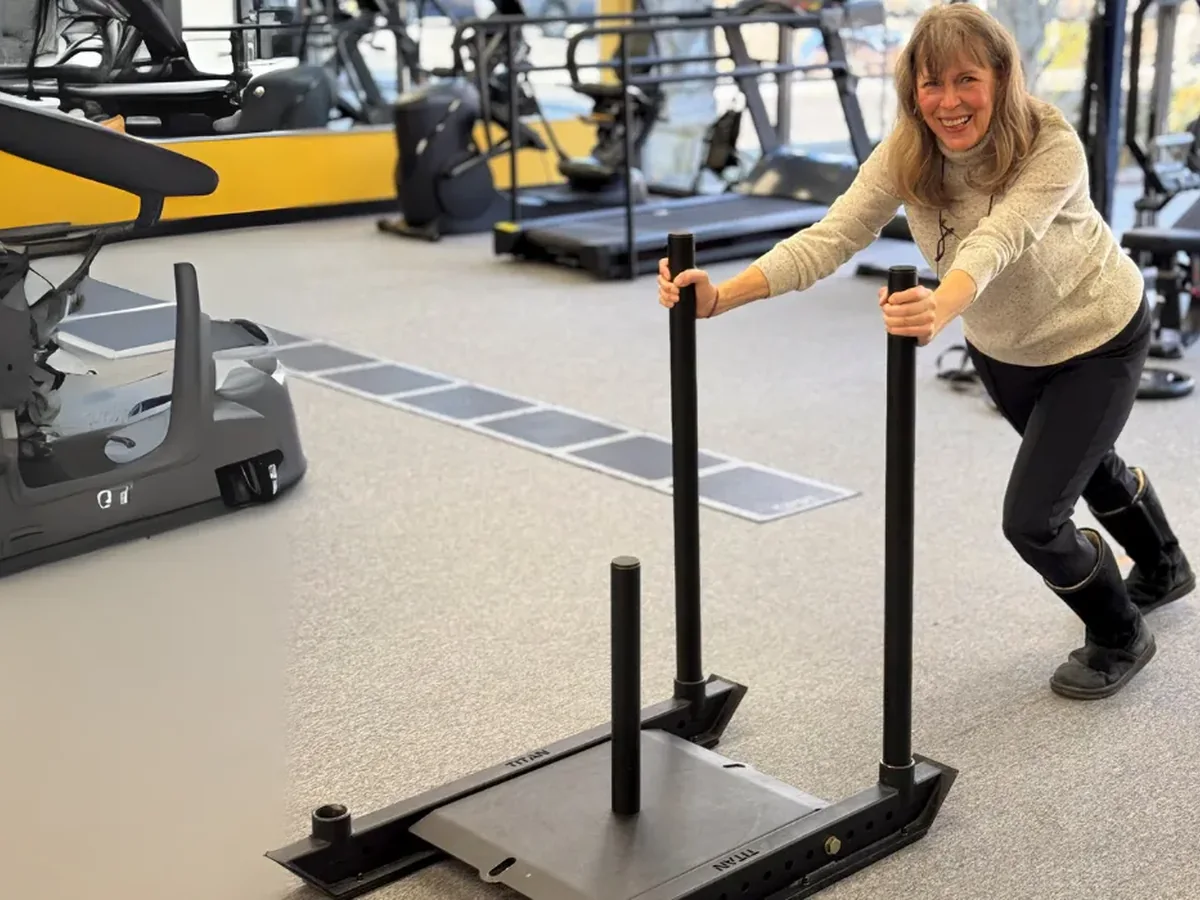 A patient pushing a weighted sled across the gym floor at Greiner Physical Therapy in Speonk, NY